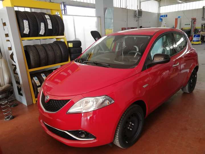 Auto rossa in officina accanto agli pneumatici